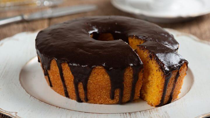 Bolo de cenoura com cobertura de chocolate servido em prato branco