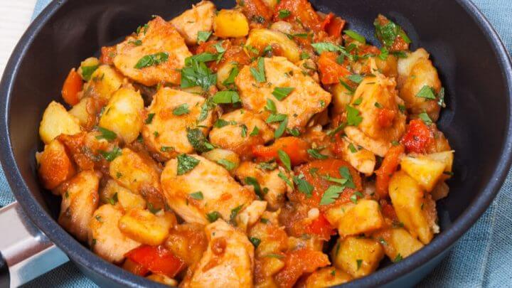Frango com vegetais em uma frigideira preta