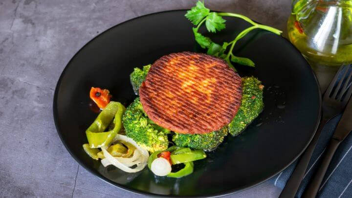 Hambúrguer de salmão em prato acompanhado por salada