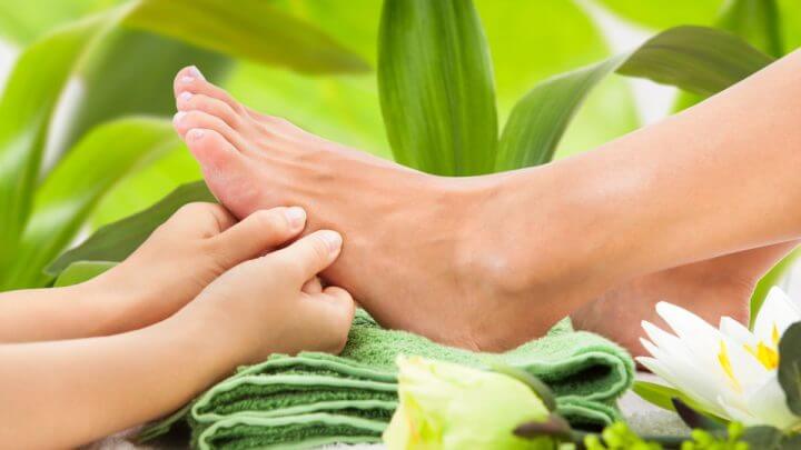 Mãos femininas fazendo massagem em um pé