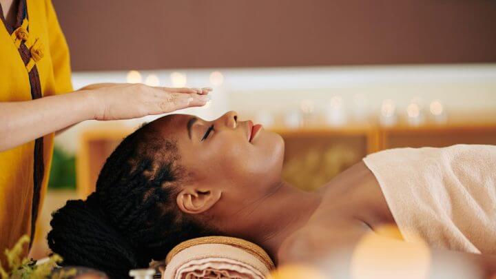 Terapeuta aplicando a prática de reiki em uma mulher deitada
