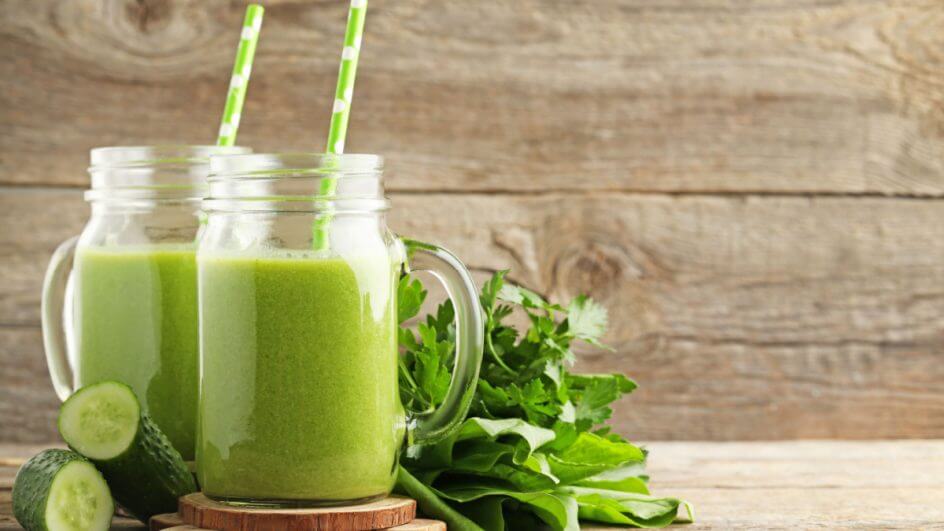 Suco verde em copo de vidro com canudo verde