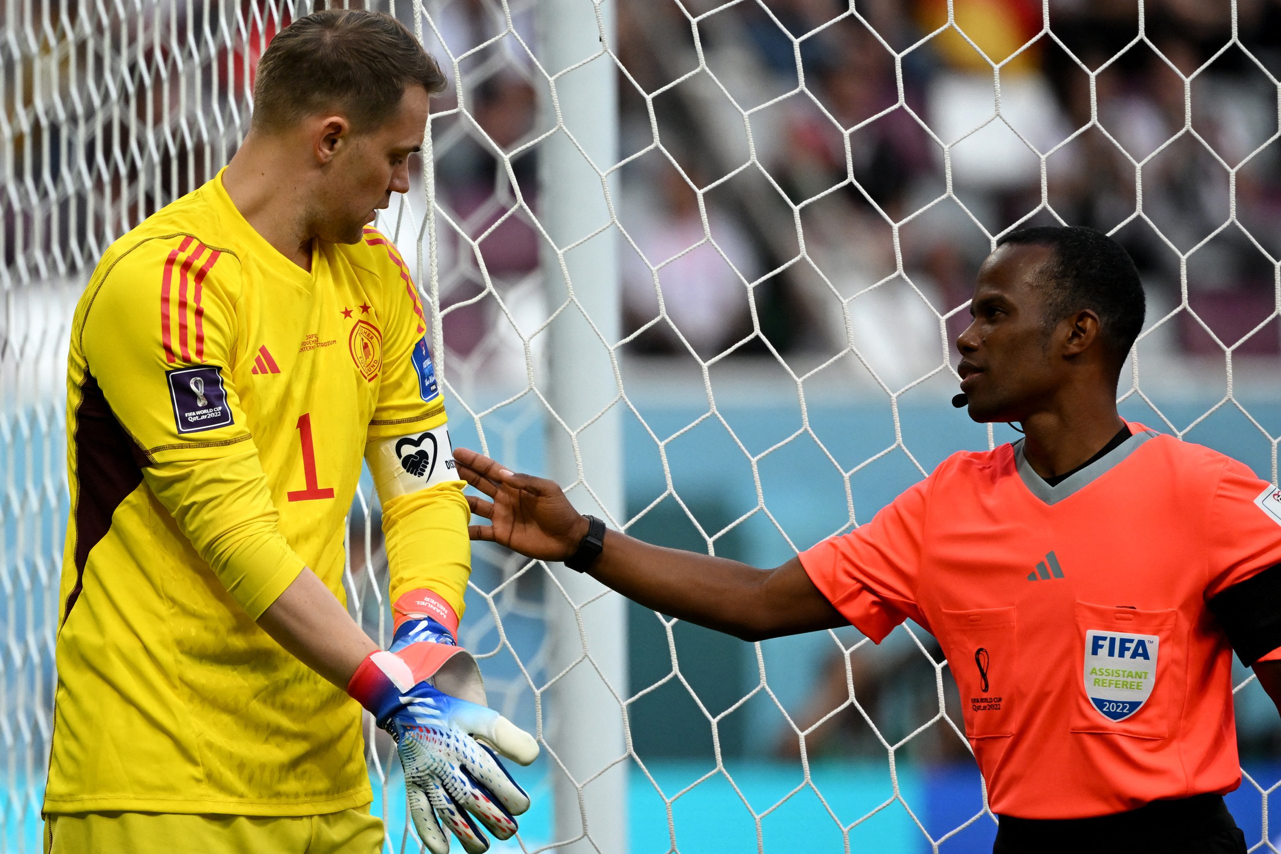 Arbitragem confere braçadeira de Neuer antes de jogo contra Japão na Copa do Catar (Foto: INA FASSBENDER / AFP)