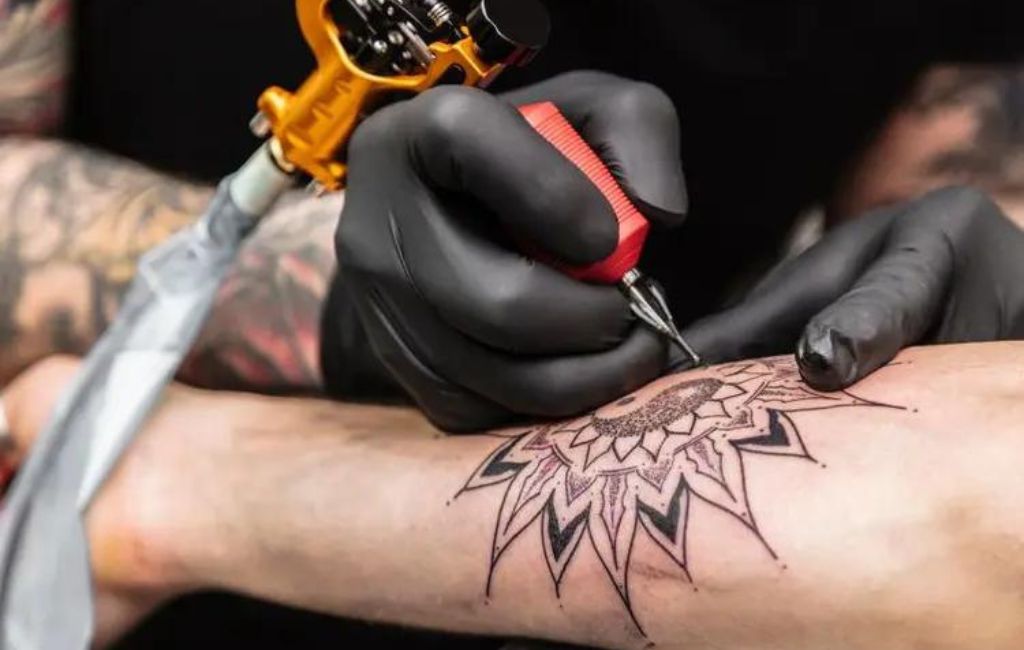 Imagem mostra um homem sendo tatuadoa