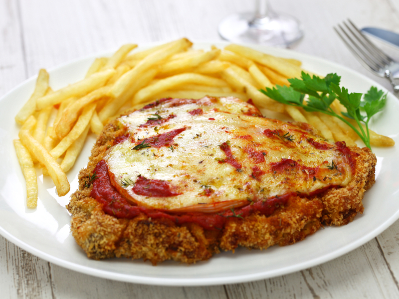 Milanesa napolitana em prato branco com batata frita ao lado