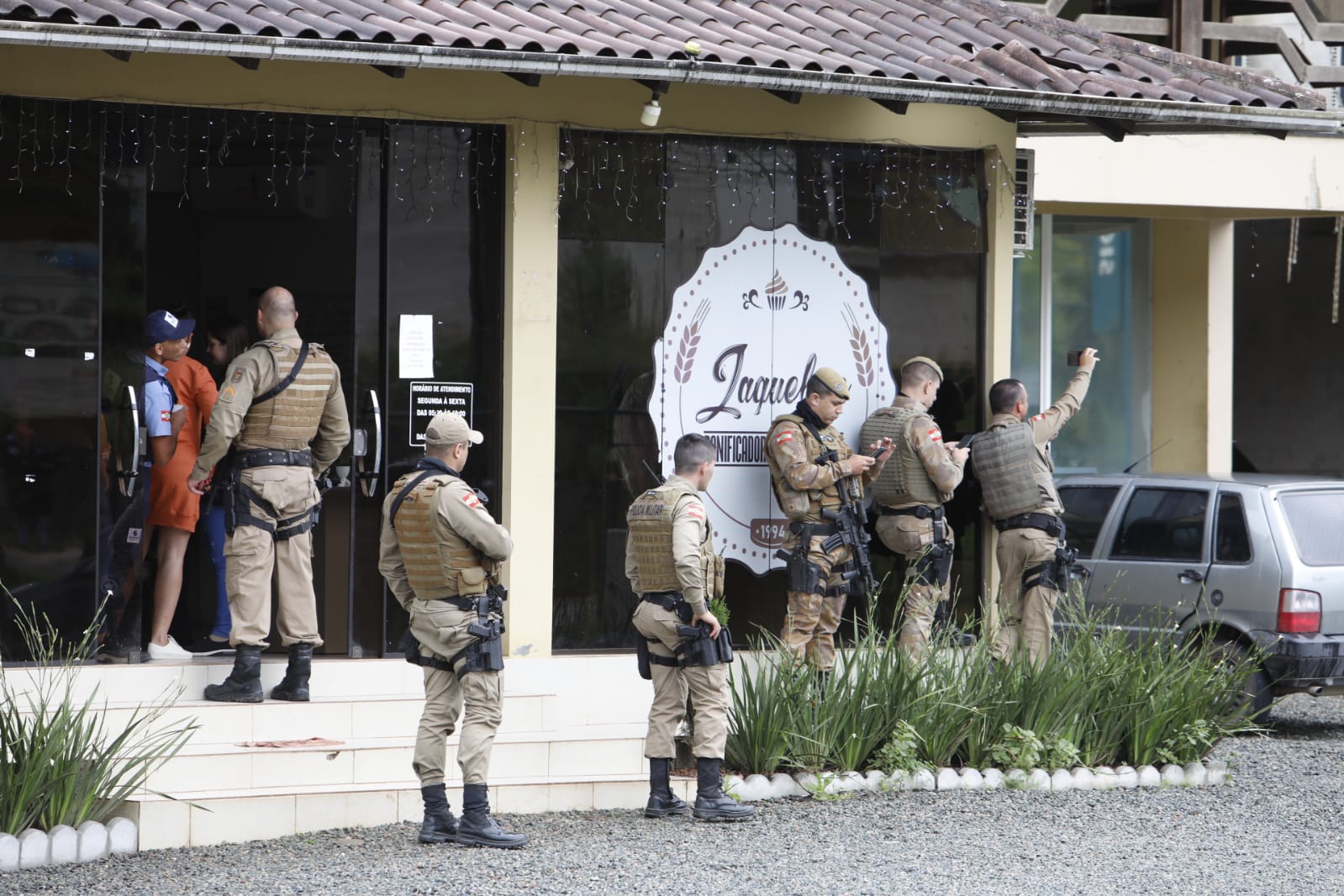 Policiais diante da padaria onde bandidos tomaram café, ao lado da cooperativa