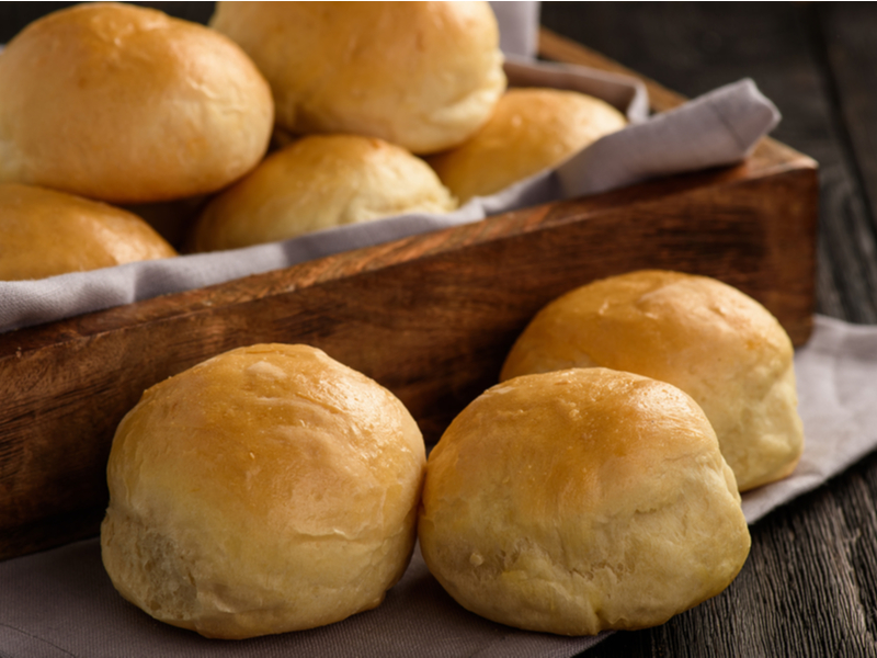 Pães de batata dentro da cesta de madeira e três pães ao lado