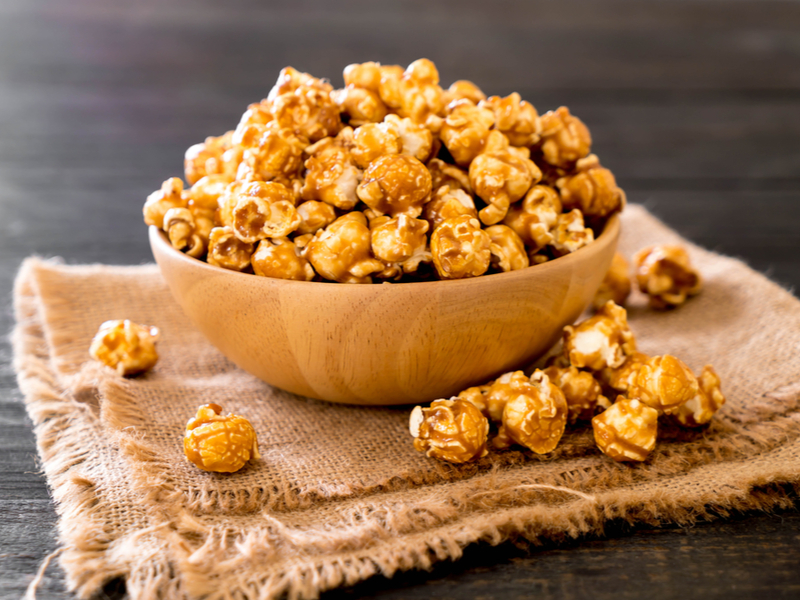 Bowl marrom cheio com pipoca caramelizada em cima do pano marrom