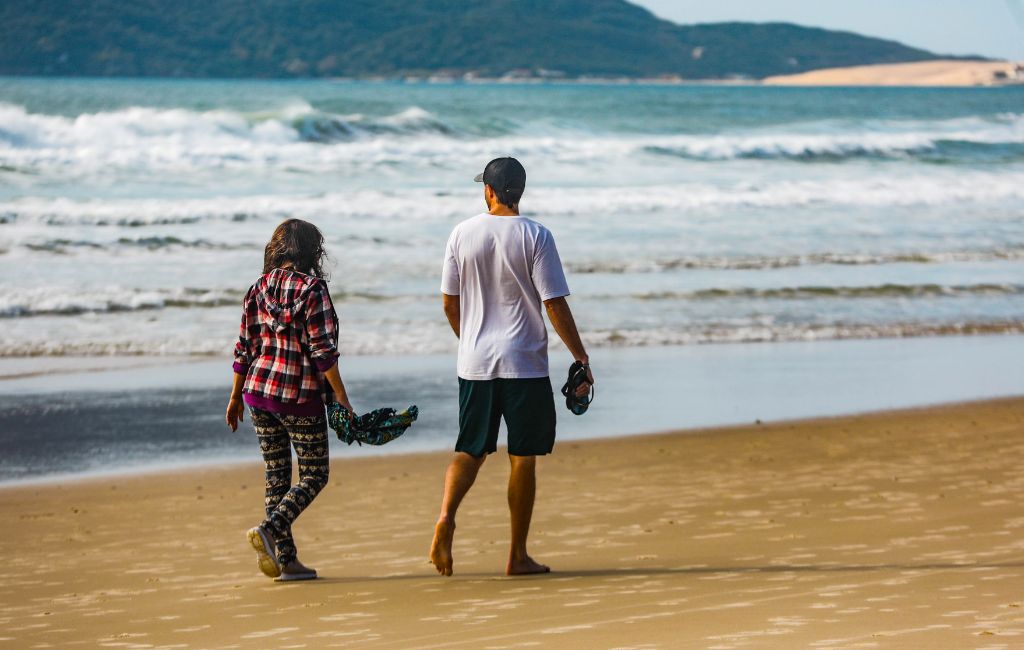 Duas pessoas caminhando na praia em Florianópolis