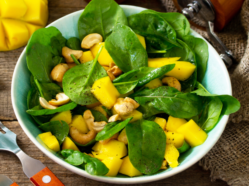 Salada com folhas de espinafre, pedaços de manga e castanha-de-caju