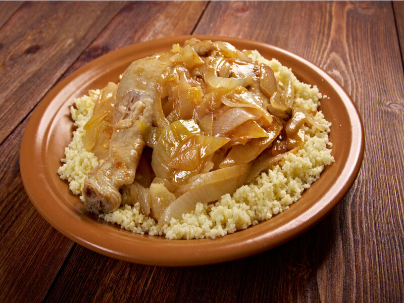 Poulet yassa em um prato marrom com cuscuz