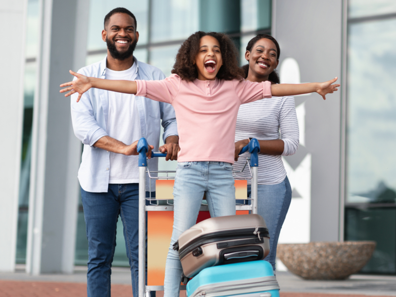 Família feliz em um aeroporto com carinho de mala