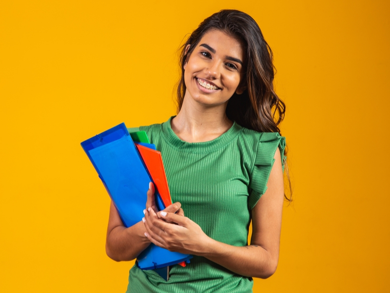 Mulher sorrindo segurando livros