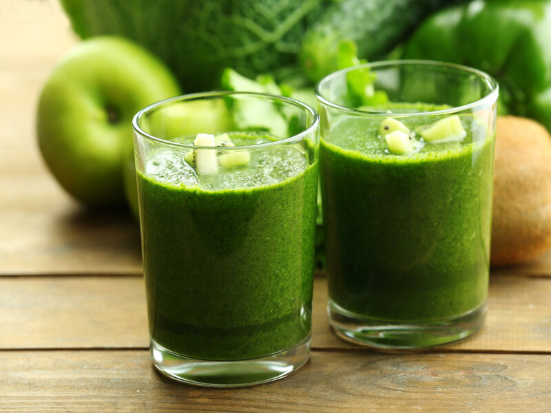 Suco verde em um copo transparente decorado com pedaços de kiwi