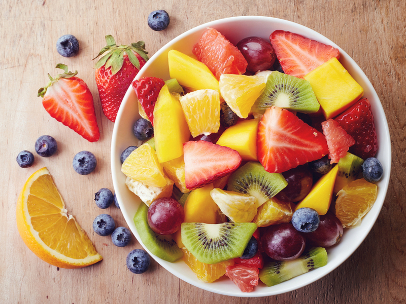 Salada de frutas dentro do bowl branco no fundo de madeira