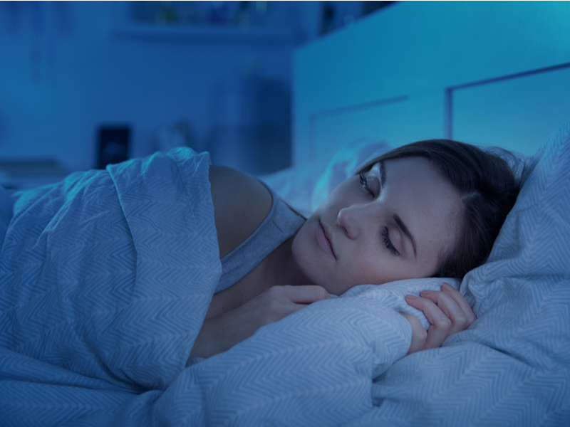 Mulher dormindo em cama com travesseiro e cobertor