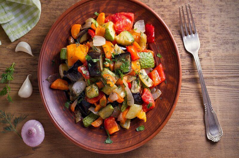 Prato marrom com tomate, berinjela e abobrinha