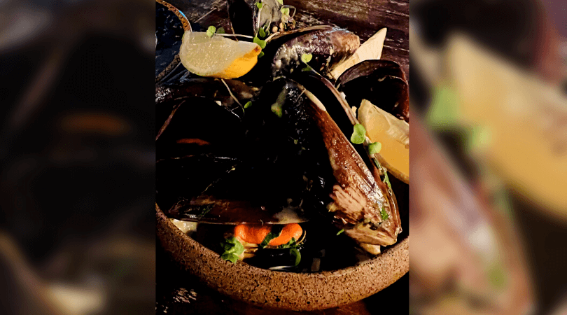 Imagem de cima de mariscos com molho de mostarda emuma tigela de cerâmica.