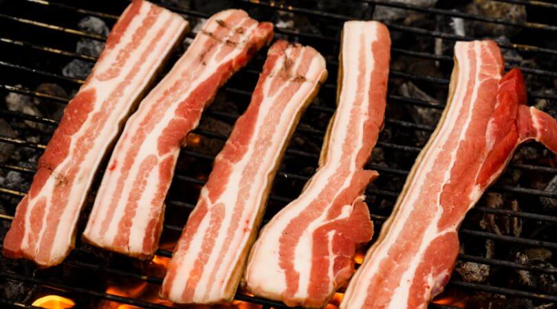 Fatias de bacon em cima da grelha de churrasqueira