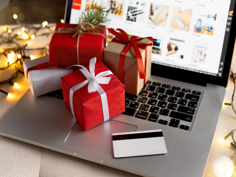 Notebook com cartão e caixinhas de presente em cima do teclado