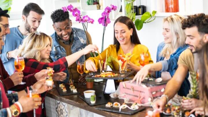 Grupo de amigos reunidos na cozinha e com diversos alimentos em cima da mesa