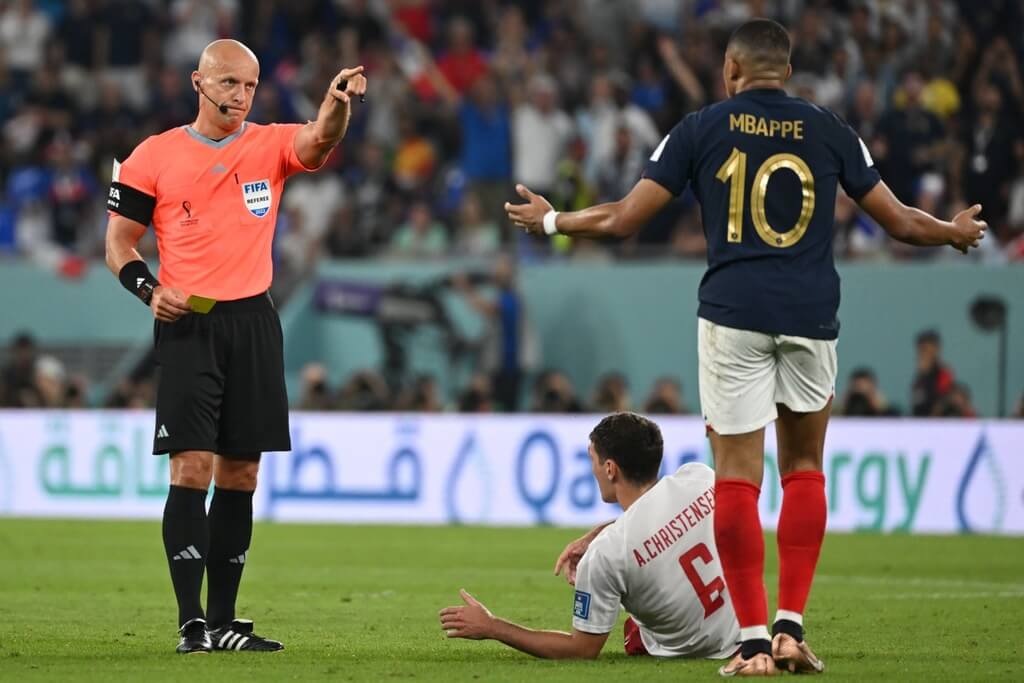 Szymon Marciniak dando cartão amarelo para Mbappé em França contra Polônia
