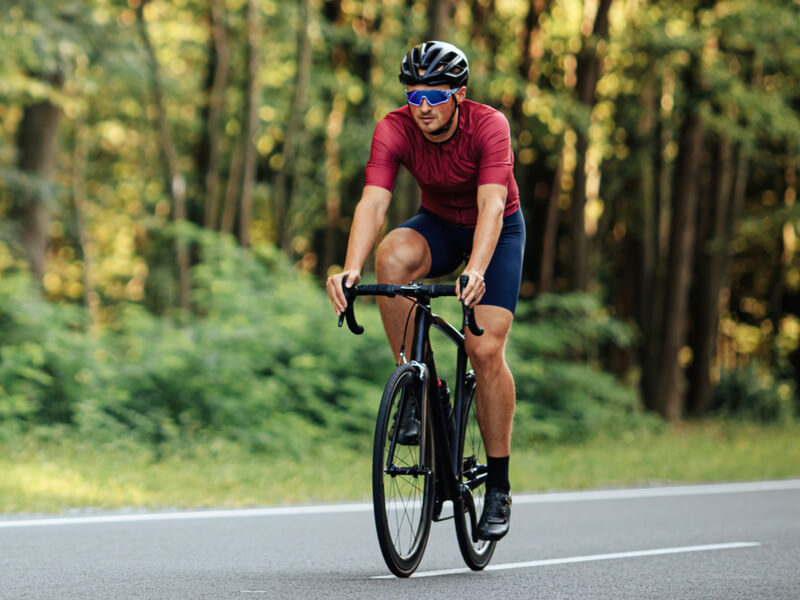 Homem andando de bicicleta e usando capacete e óculos