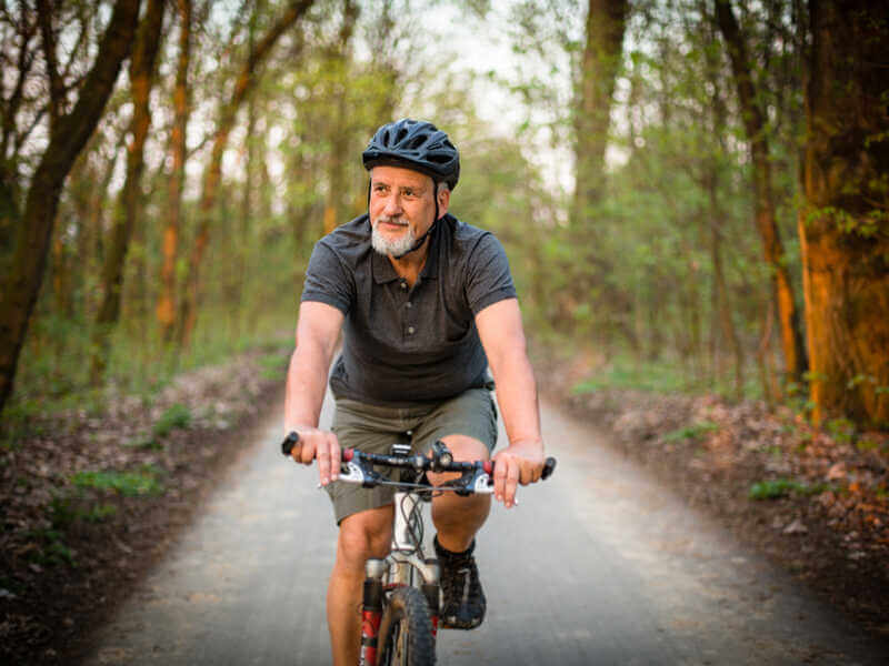 Homem andando de bicicleta ao ar livre e usando capacete