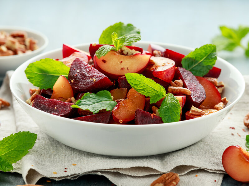 Salada de ameixa, beterraba e com folhas de hortelã no bowl branco