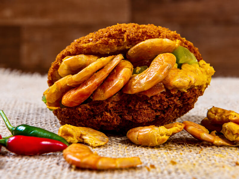 Acarajé com camarão em superfície branca e pimenta vermelha e verde ao lado