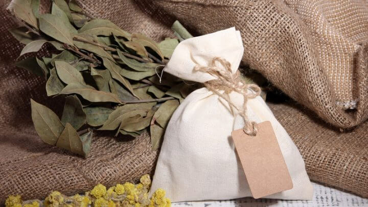 Saquinho de pano branco com fundo com tecido e plantas secas