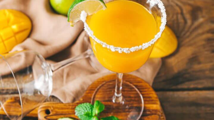 Taça de vidro com margarita de manga e decorada com açúcar e fatia de limão