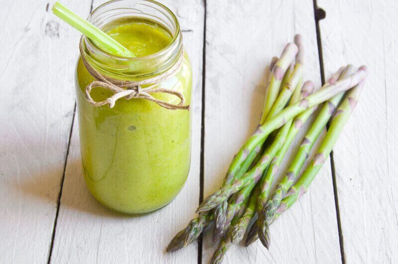 Copo de vidro suco verde e aipos ao lado