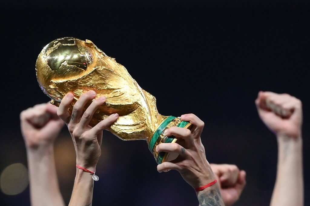 Foto com foco na taça da Copa do Mundo, sendo levantada por Angel Di Maria