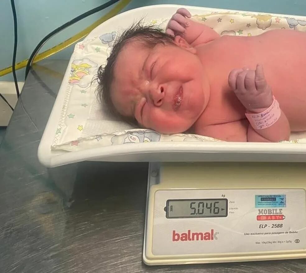 Bebê Maria Vitória na balança, pensando 5,046 kg