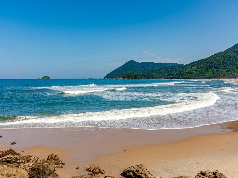 Imagem panorâmica de uma praia com montanha em Bertioga