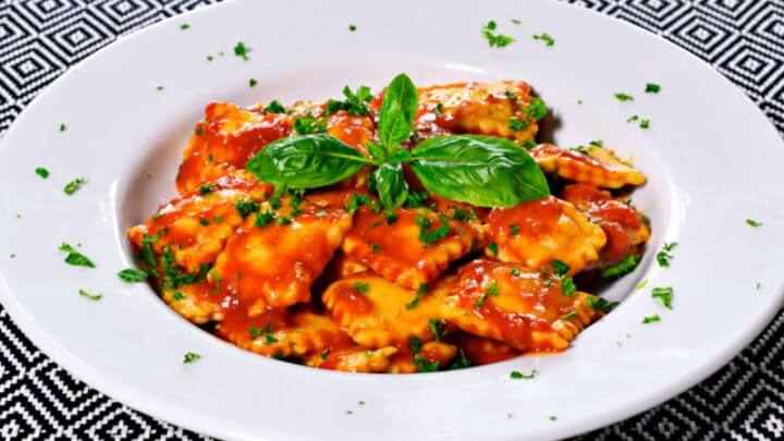 Ravióli com molho de tomate e manjericão em prato branco