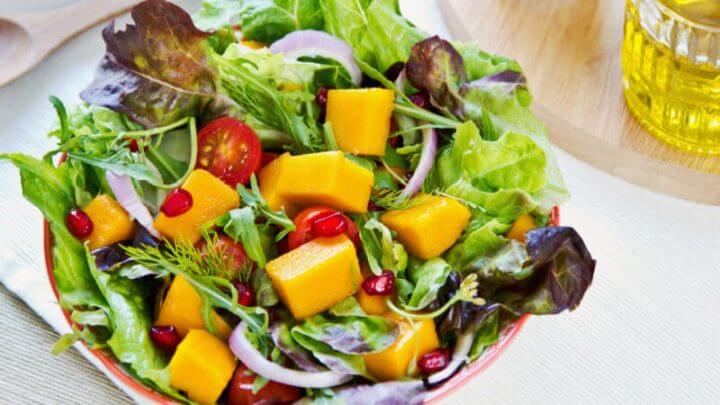 Salada com manga, sementes de romã, alface, cebola e tomate