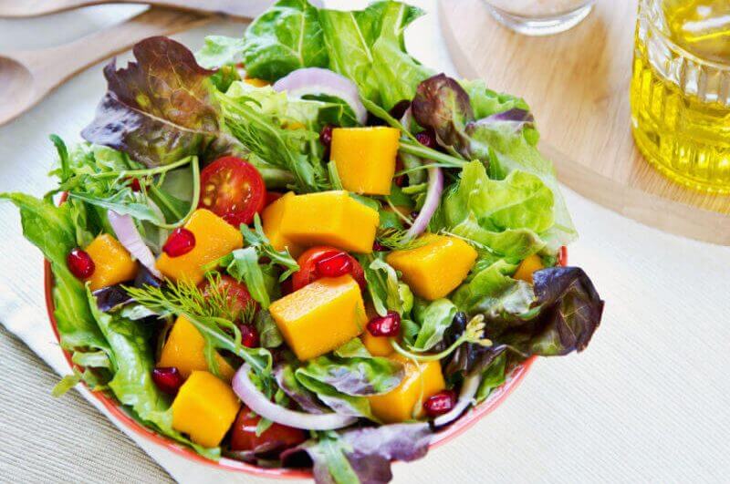 Salada com manga, sementes de romã, alface, cebola e tomate