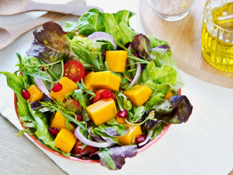 Salada com manga, sementes de romã, alface, cebola e tomate