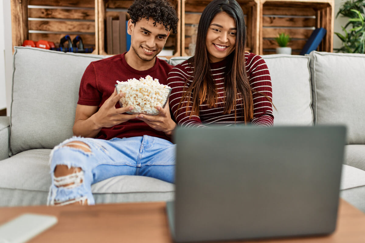 Jovens com balde de pipoca assistindo filmes