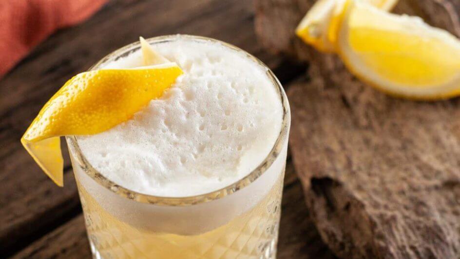 Drink Whisky Sour em copo de vidro com casca de limão
