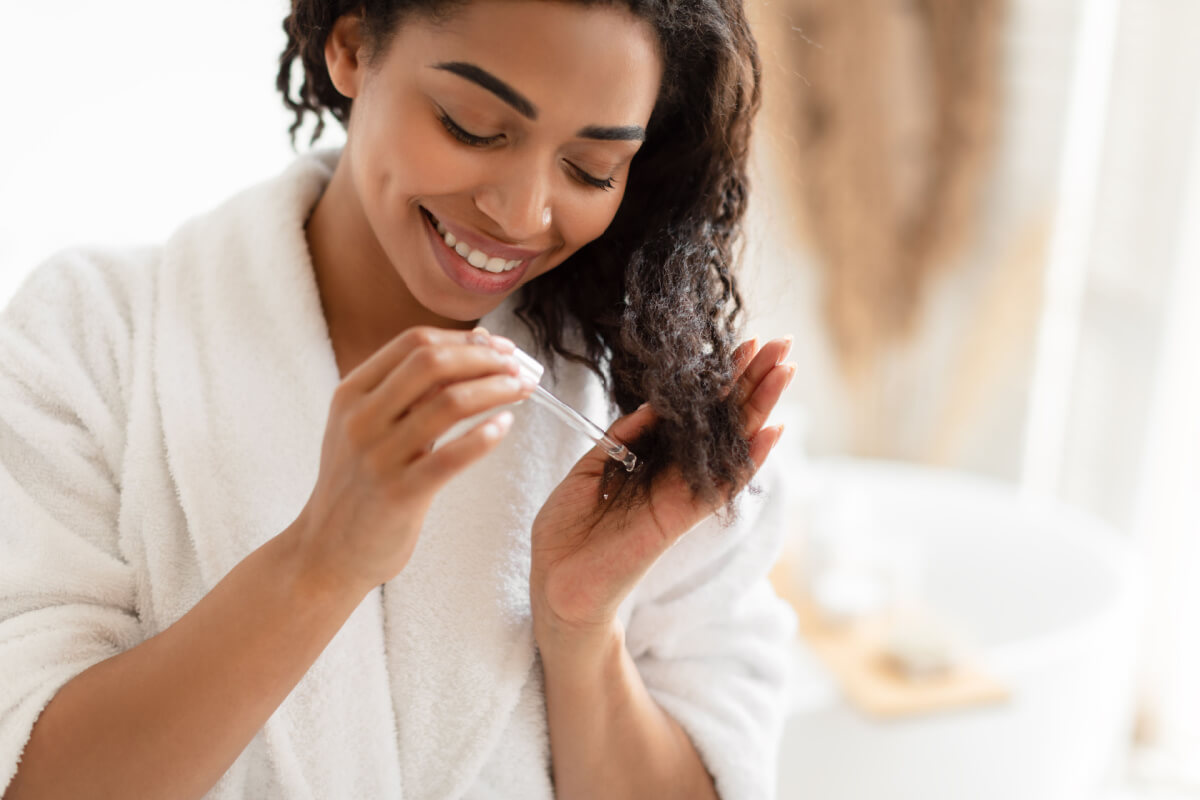 mulher passando óleo no cabelo