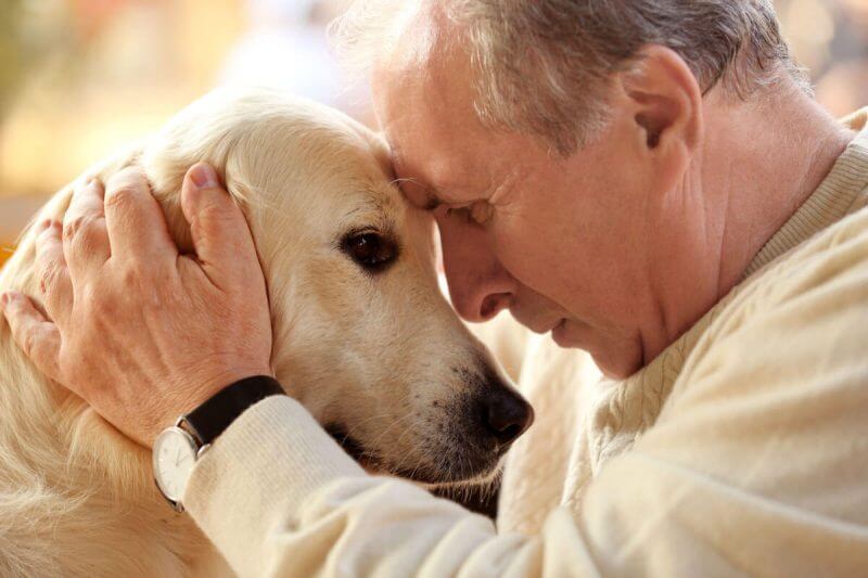 Um senhor abraçado com seu cão