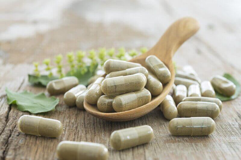 Cápsulas de suplementos alimentares em cima de uma mesa de madeira