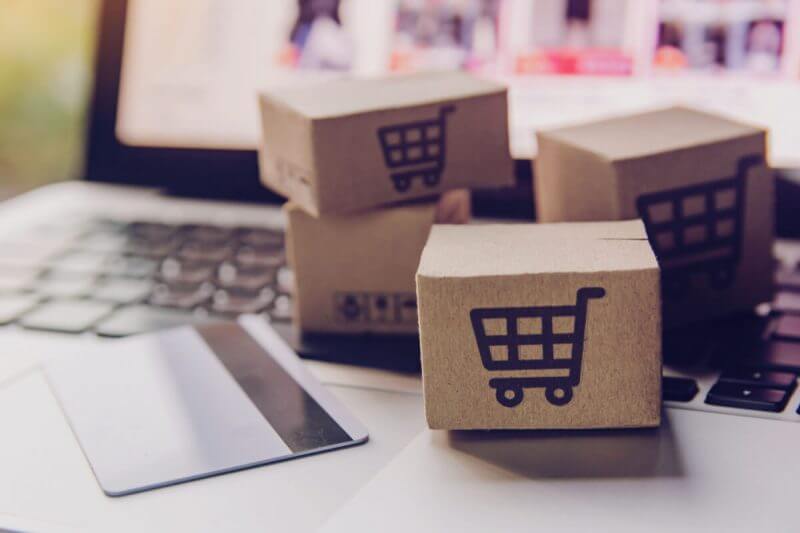 caixas de papel ou pacote com o logotipo do carrinho de compras e cartão de crédito no teclado do laptop