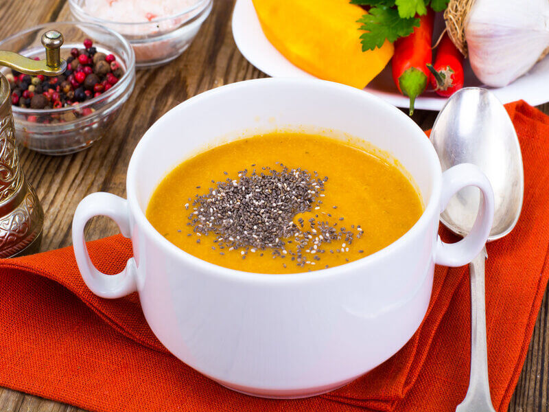 Creme de abóbora em uma panela branca com sementes de chia