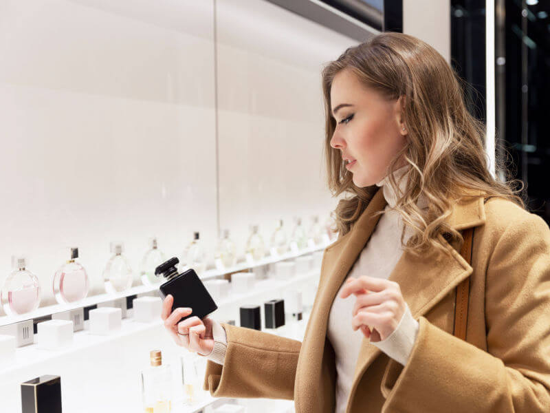 Mulher escolhendo perfume na prateleira