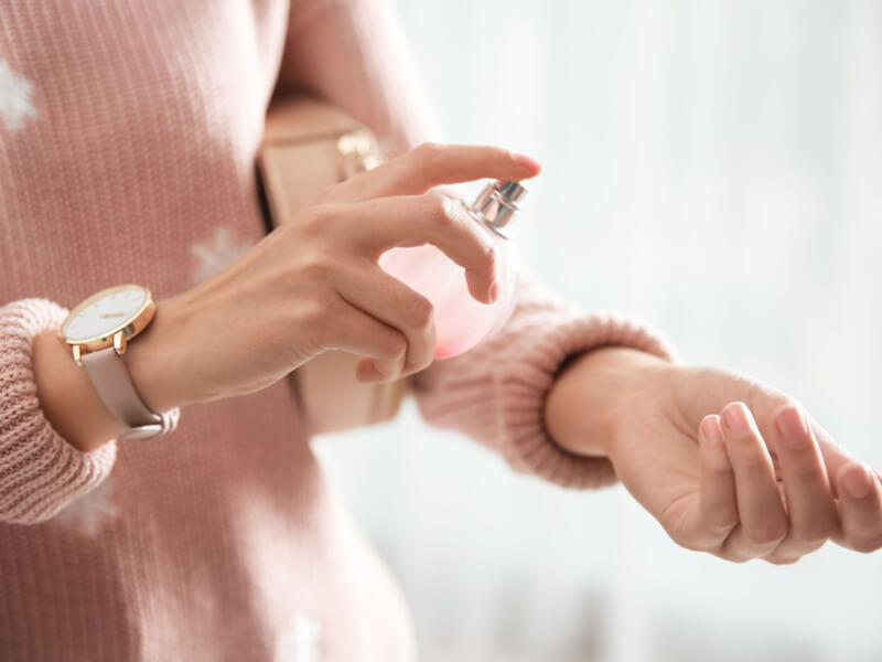 Imagem de uma mulher aplicando perfume no pulso