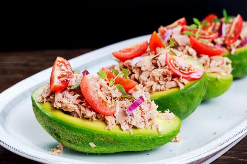 Abacate recheado com atum em cima de um prato branco